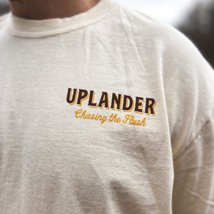 Front chest detail of an off-white t-shirt with text 'Uplander, Chasing the Flush'.