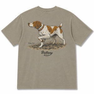Back view of a tan t-shirt featuring a detailed illustration of an orange and white Brittany on point, with 'Brittany', 'Heritage Series' and 'Uplander' text.