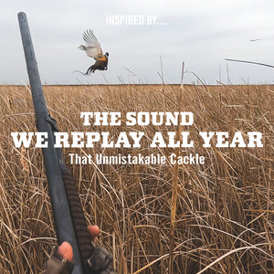 Hunter raising a shotgun as a ring-necked pheasant flushes from a grass field, with text 'The Sound We Replay All Year, That Unmistakable Cackle'.