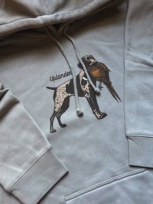 Flat lay of a grey hoodie featuring a graphic of a liver and roan German Shorthaired Pointer holding a ring-necked pheasant in its mouth with Uplander branding.