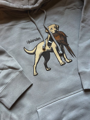 Flat lay of a grey hoodie featuring a graphic of a yellow Labrador Retriever holding a ring-necked pheasant in its mouth with Uplander branding.