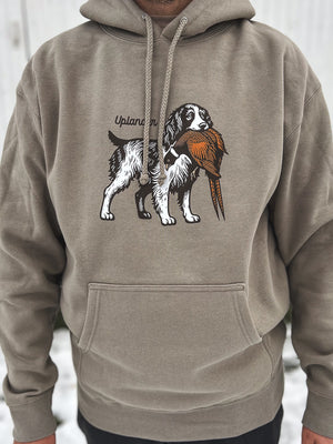 Man wearing a grey hoodie featuring a graphic of an English Springer Spaniel holding a ring-necked pheasant in its mouth with Uplander branding.
