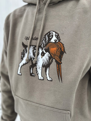 Close-up view of a man wearing a grey hoodie featuring a graphic of an English Springer Spaniel holding a ring-necked pheasant in its mouth with Uplander branding.