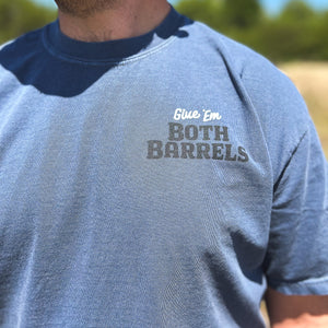 Front chest detail of a blue t-shirt  with 'Give 'Em Both Barrels' text, worn outdoors.
