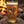 The King Heritage Series 001 pint glass filled with beer, featuring a ruffed grouse illustration, resting on rocks beside a glowing campfire.