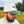 Right-side view of a man wearing an ivory and dark green two-tone snapback hat with an embroidered flying ruffed grouse and 'Ruffed Grouse' script on the front, worn outdoors.