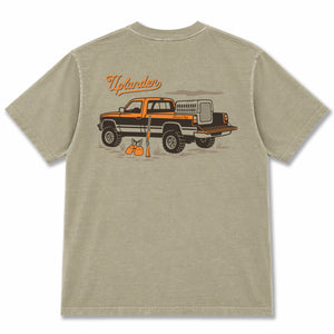 Back view of a khaki t-shirt featuring a vintage pickup truck with a dog kennel, hunting vest and shotgun with text 'Uplander, Chasing the Flush'.